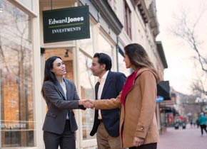 Edward Jones female Advisor shaking hands with female client outside of office while male client looks on.