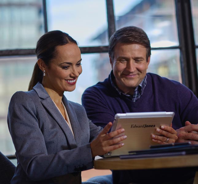 A man looks at a tablet device held by a financial advisor.
