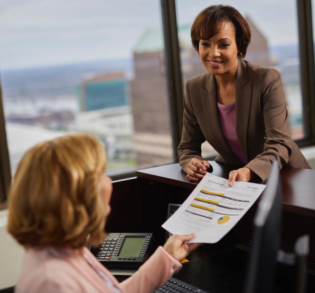 A financial advisor handing papers to an associate.