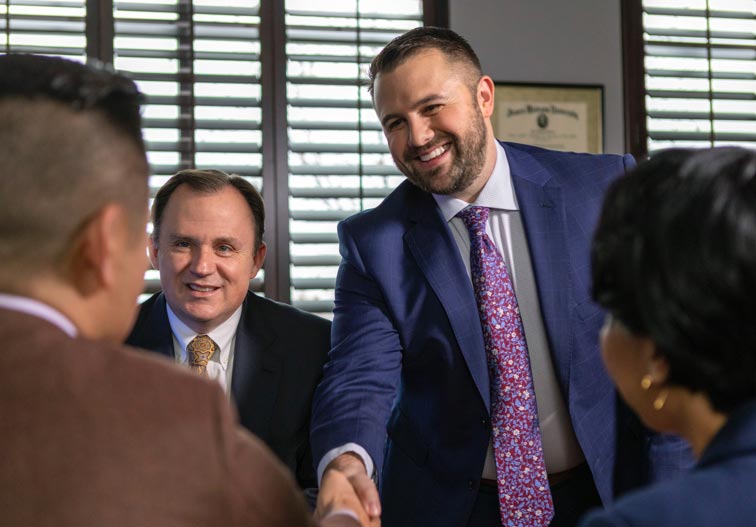 Two businessmen shaking hands with another man and woman.