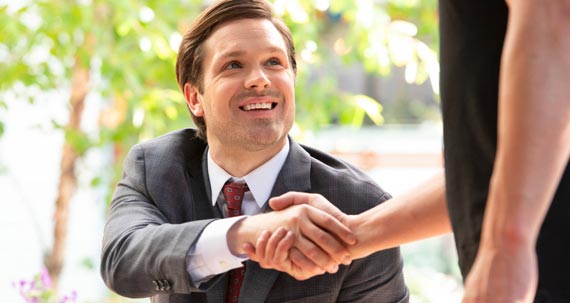 A smiling man handshake with other person