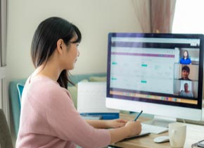 Woman facing a computer screen writing a note.