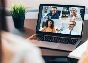 Over the shoulder shot of person viewing an online meeting on laptop screen.