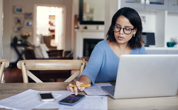 Woman using a laptop and calculator while working from home