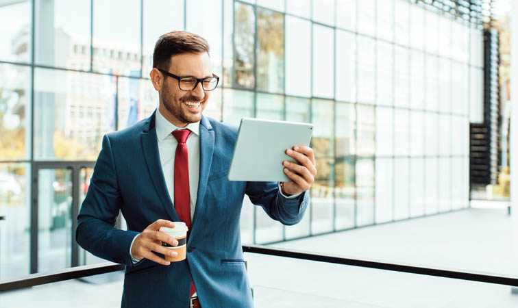Un homme d’affaires souriant et au style moderne utilise une tablette pendant la pause café.