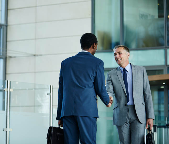 Deux hommes d’affaires se serrent la main dans le hall d’un immeuble de bureaux.