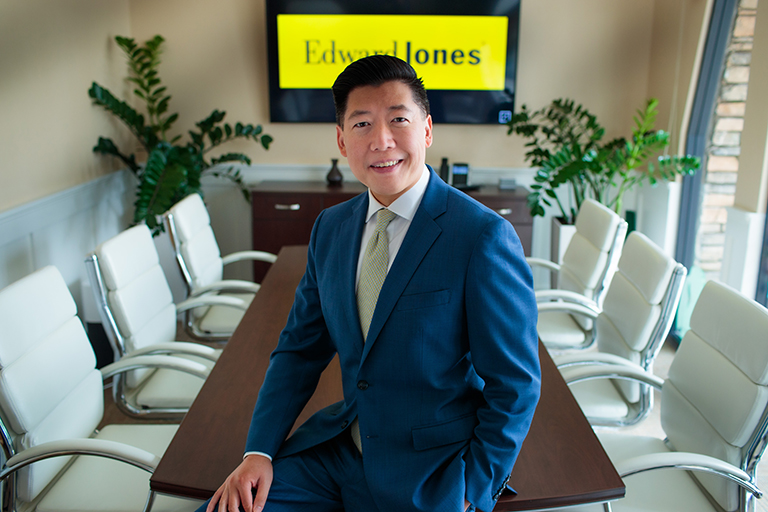 david-tam-hero Man in suit sitting on conference room table